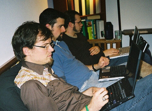yan yana oturmuş bilgisayara bakan üç adam