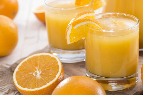 bardakta portakal suyu ve yanında dilimlenmiş portakallar