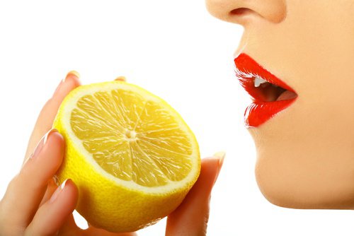 yarım limonu ısırmak üzere olan kadın