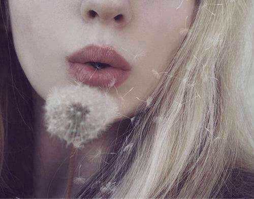 karahindiba çiçeği üfleyen kadın