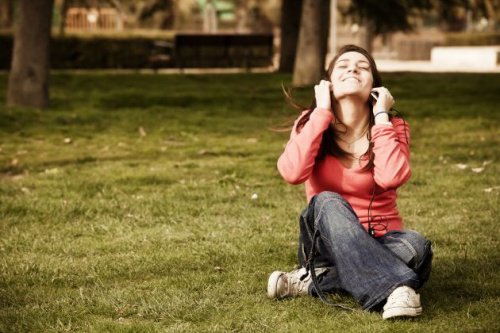 çimde oturarak müzik dinleyen kadın