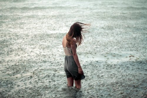 yağmur altında nehirde yürüyen yalnız kadın