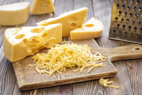 kesme tahtasının üstünde üçgen dilim ve rendelenmiş peynir