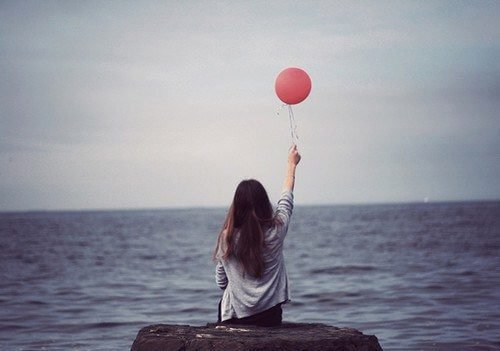 sahil kenarında balon tutarak oturan kız