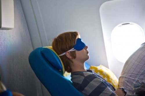 koltuğunu yatırmış bir genç ve uçakta uyumak