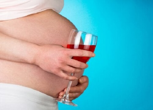 Bir şarap kadehi tutan hamile bir kadın.