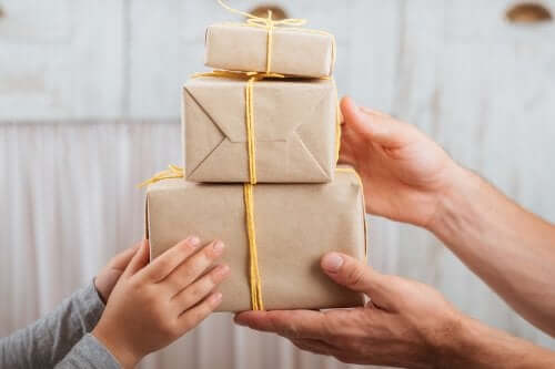 Farklı boyutlarda üç hediye kutusunu tutan iki çift el.