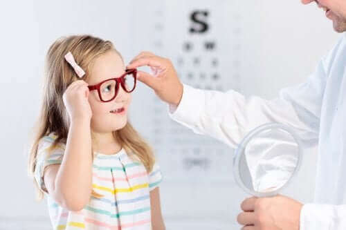 Göz doktoru ile birlikte gözlük deneyen bir kız çocuğu.