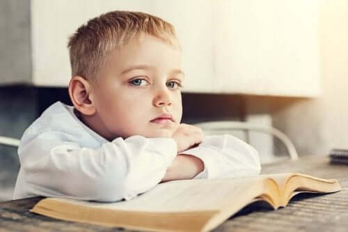 Kitabının üzerine yatmış, sıkkın görünen bir oğlan çocuğu.