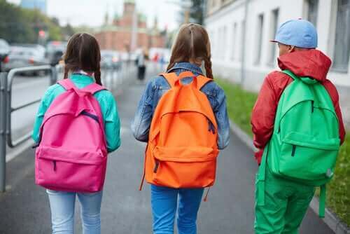 pembe, turuncu ve yeşil sırt çantaları takan üç çocuk