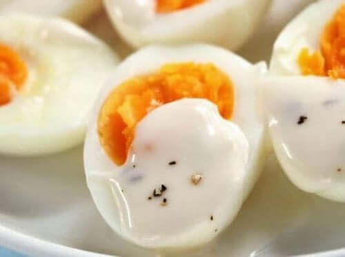 Haşlanmış yumurtanın üstüne koyulmuş yoğurt sosu.