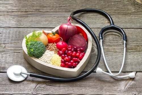 kalp şeklindeki kasede sağlıklı meyve ve sebzeler ve etraflarında bir stetoskop