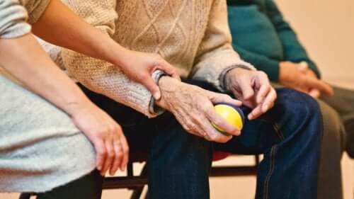 Parkinson hastalığı olan bir adamın elini tutan bir kadın.