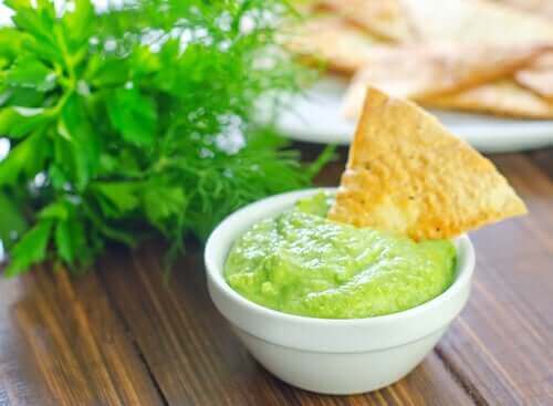 Avokado sosuna batırılmış bir cips parçası.