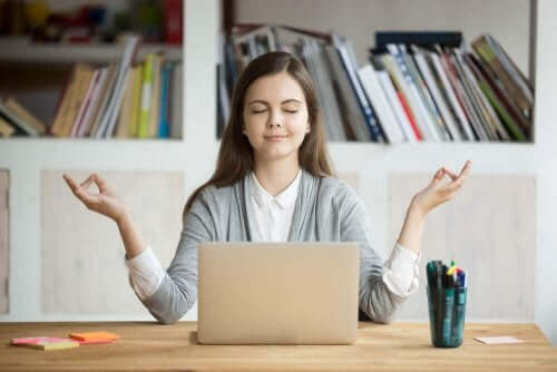 Bilgisayarının önünde meditasyon yapan bir kadın.