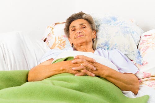 Azheimer hastalığı olan, yatağında uyanık yatan yaşlı bir kadın.