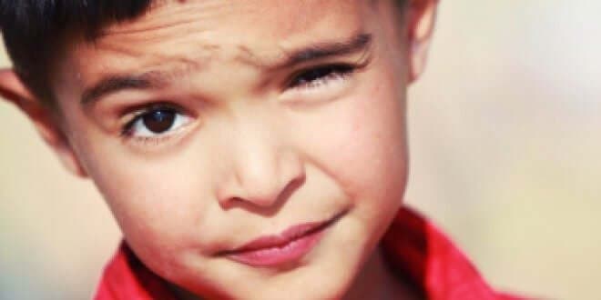 Kırmızı tişörtlü yüzünü ekşiten çocuk