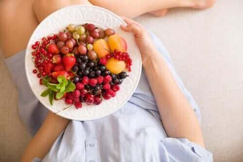 Meyve ve sebze yiyen hamile bir kadın.