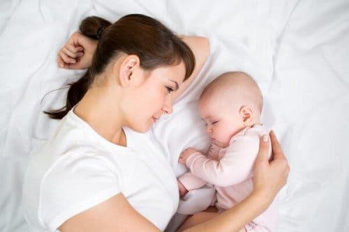 Bebeğinin yanına yatmış, onu izleyen bir anne.