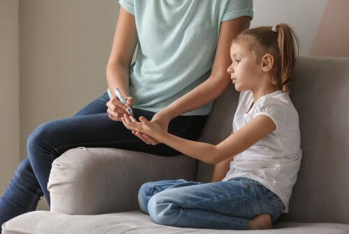 Diyabeti olan, kan şekeri ölçülen bir kız çocuğu.