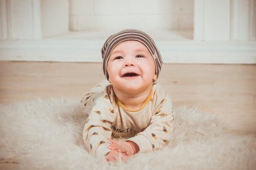 Halıda yatmış, gülen bir bebek.