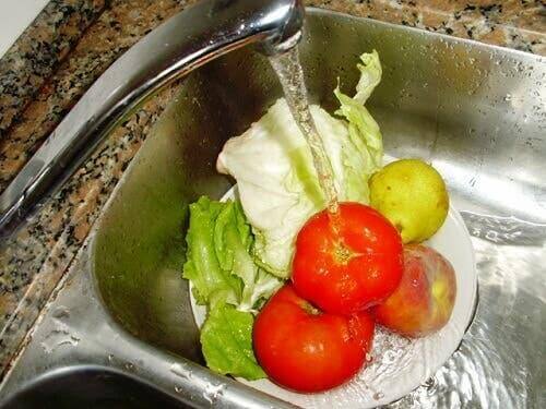 Meyve ve sebzelerini lavaboda yıkayan biri.