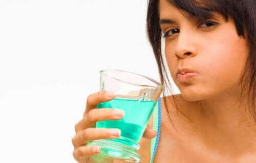 Ağız bakım suyu ile ağzını çalkalayan bir kişi.