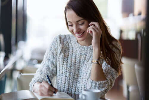 Önündeki deftere bir şeyler yazan mutlu bir kadın.