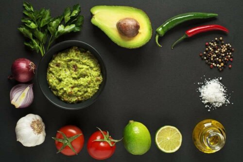 Bir kase guacamole ve guacamole yapmak için kullanılan malzemeler.