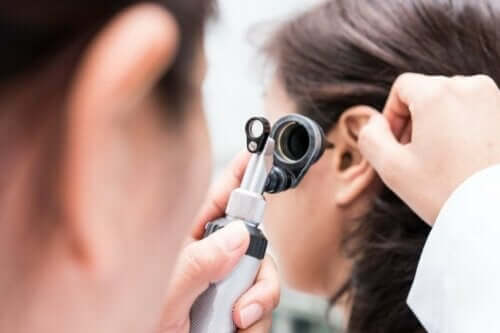 Bir kişinin kulağını muayene eden bir doktor.