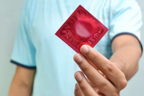 Elinde bir prezervatif tutan bir kişi.
