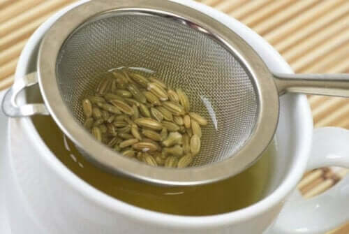 Süzgeçteki rezene tohumları ile demlenen bir kupa çay.