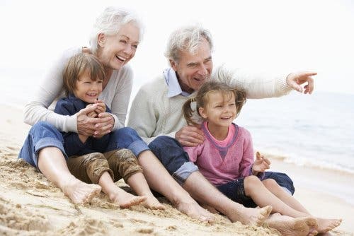 Torunlarıyla plajda oturan bir büyükanne ve büyükbaba.