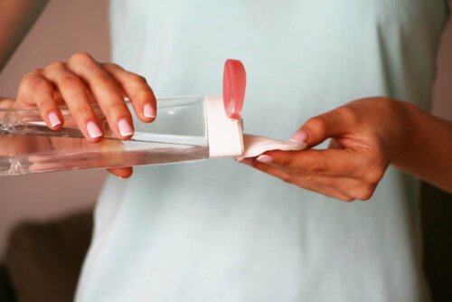 Bir parça pamuğa elindeki şişeden misel suyu döken bir kadın.