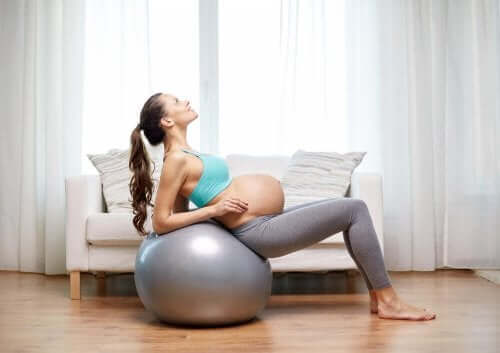 Bir egzersiz topu kullanan hamile bir kadın.