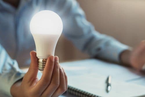 Elinde LED ampul tutan bir kişi.