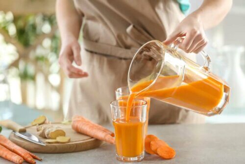 Sürahiden bardağa havuçlu smoothie döken bir kadın.