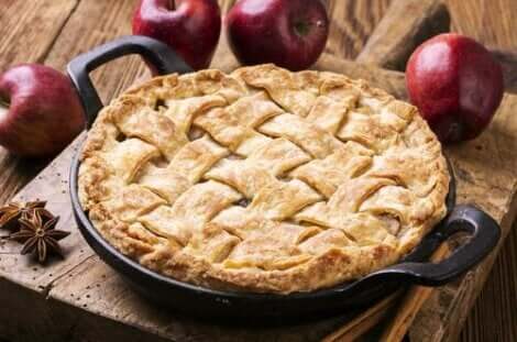 masanın üzerinde pişmiş bir turta ve birkaç elma duruyor