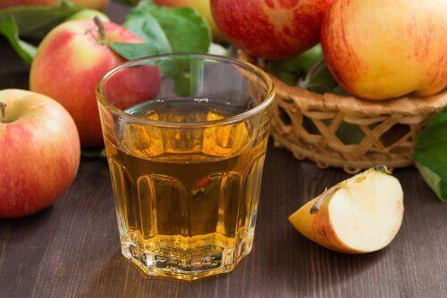 Bir bardak elma suyu ve yanındaki elmalar.