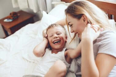 Bir anne çocuğuyla beraber yatakta kahkaha atıyor.