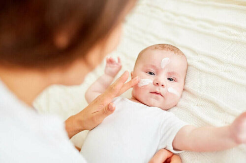 Bebeğinin yüzüne krem süren bir anne.