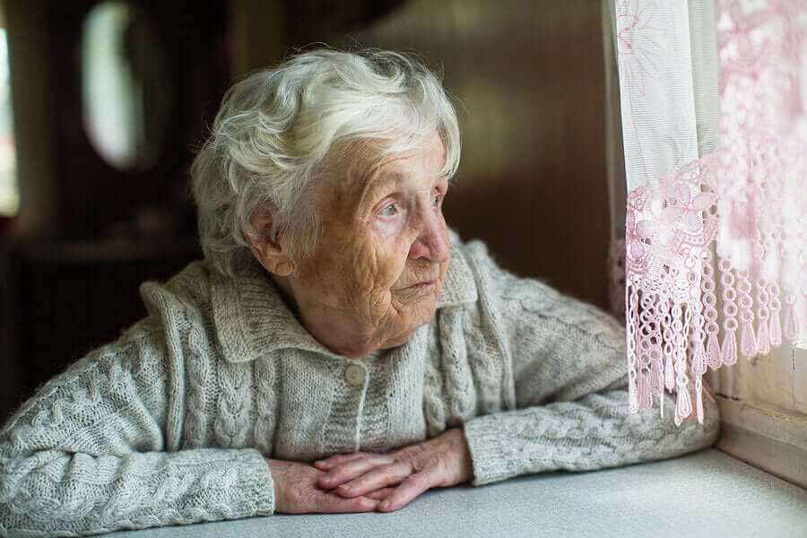 camdan bakan üzgün yaşlı kadın