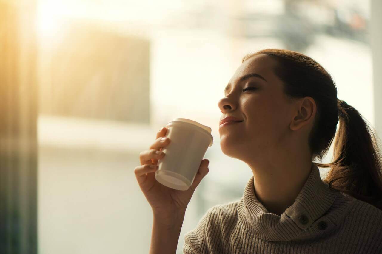kahvesini koklayan mutlu kadın