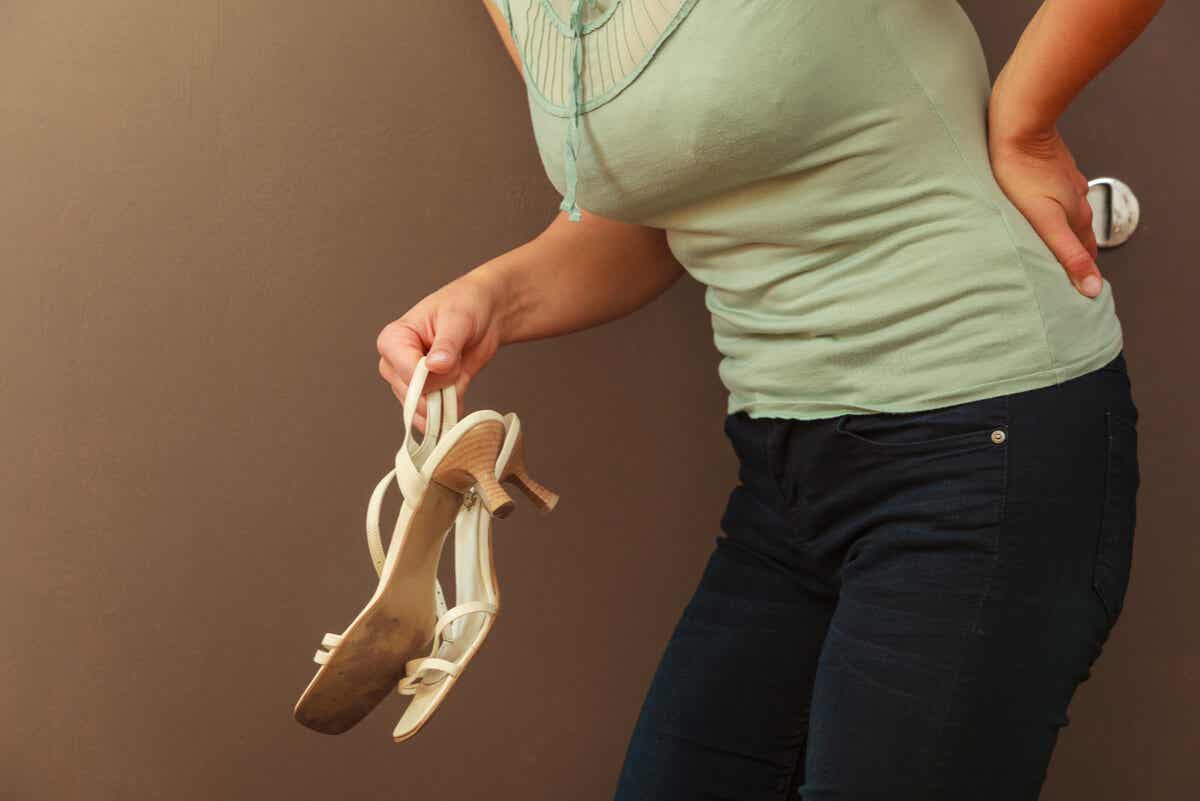 topuklu ayakkabı tutarken beli ağrıyan kadın